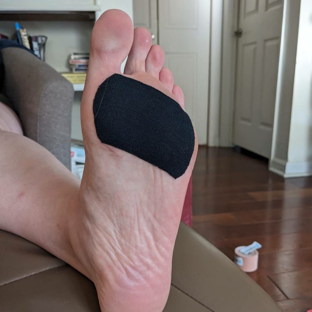 Kinesiology tape stretched like a bandaid across the bottom of the ball of the foot can relieve pain in this area and between the toes.